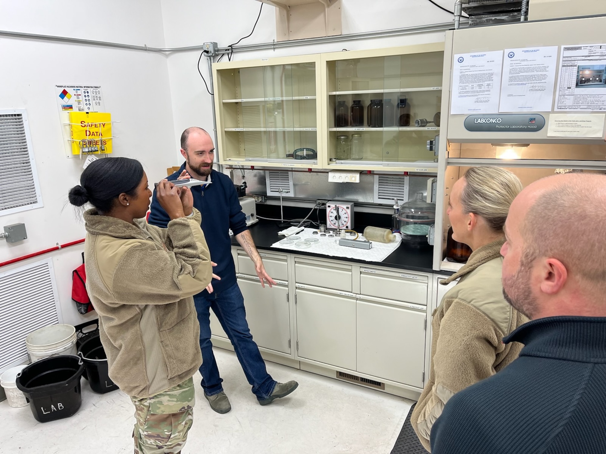 A group of people stand in a lab and converse.