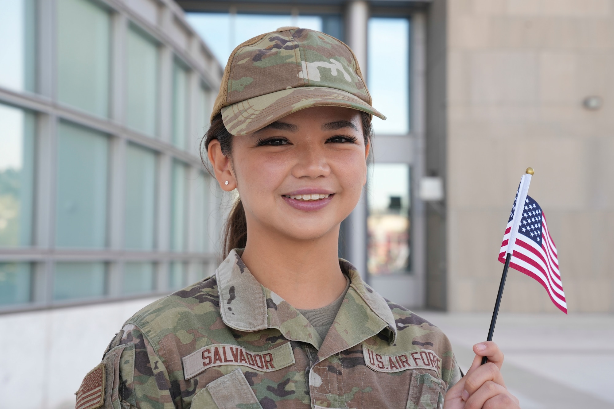Airman 1st Class Elisa Salvador smiles at the camera while holding an American flag.