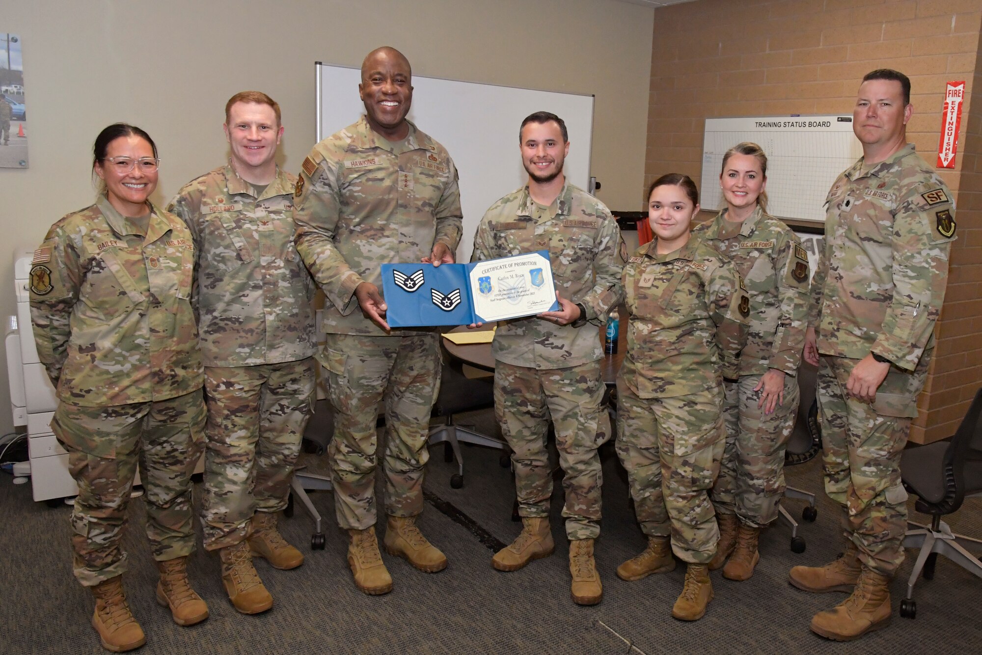 Lt. Gen. Hawkins and Staff Sgt. Roca hold a certificate while posing for a group photo with wing leadership and other members of the squadron.