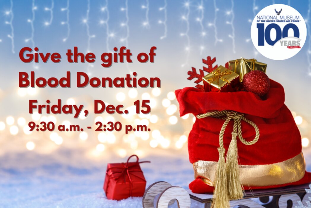 Give the gift of Blood Donation, Friday Dec. 15 from 9:30 a.m. - 2:30 p.m. in red letters on a light blue background with white snow on the ground and strands of white lights in the backgroun. In the foreground is a red sack of presents with gold trip.