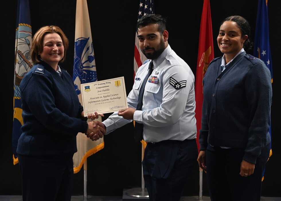U.S. Air Force Col. Angelina Maguinness, 17th Training Wing commander, presents Senior Airman Jose Padilla, 17th Communications Squadron, with a certificate for completing his Associate in Applied Science Information Systems Technology through the Community College of the Air Force, at Goodfellow Air Force Base, Texas, Nov. 9, 2023. Padilla demonstrated a commitment to personal and professional growth, balancing his military duties with academic pursuits. (U.S. Air Force photo by Senior Airman Ethan Sherwood)