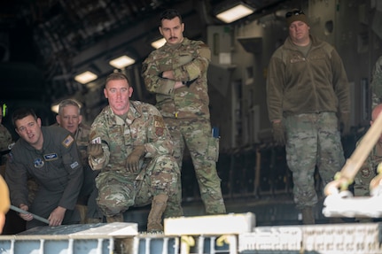 U.S. Air Force Tech. Sgt Kenneth Casey, an aircraft maintainer with the 167th Maintenance Group, directs a pallet while being observed by Master Sgt. Corbin Householder, left, 167th Operations Group loadmaster, during multicapable Airmen training at the 167th Airlift Wing, Martinsburg, West Virginia, Nov. 5, 2023. The training focused on developing competencies outside of the Airman’s primary Air Force specialty code. (