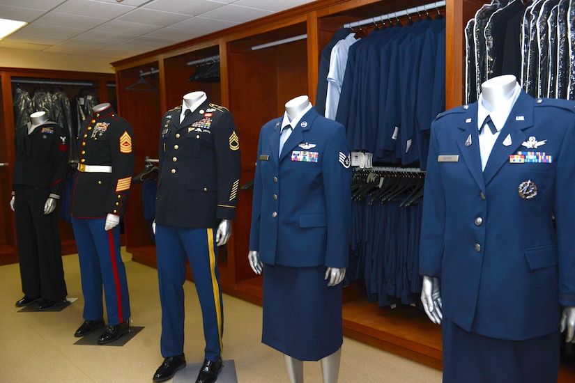 Five mannequins were various dress military uniforms. Open closets behind them hold more uniforms.