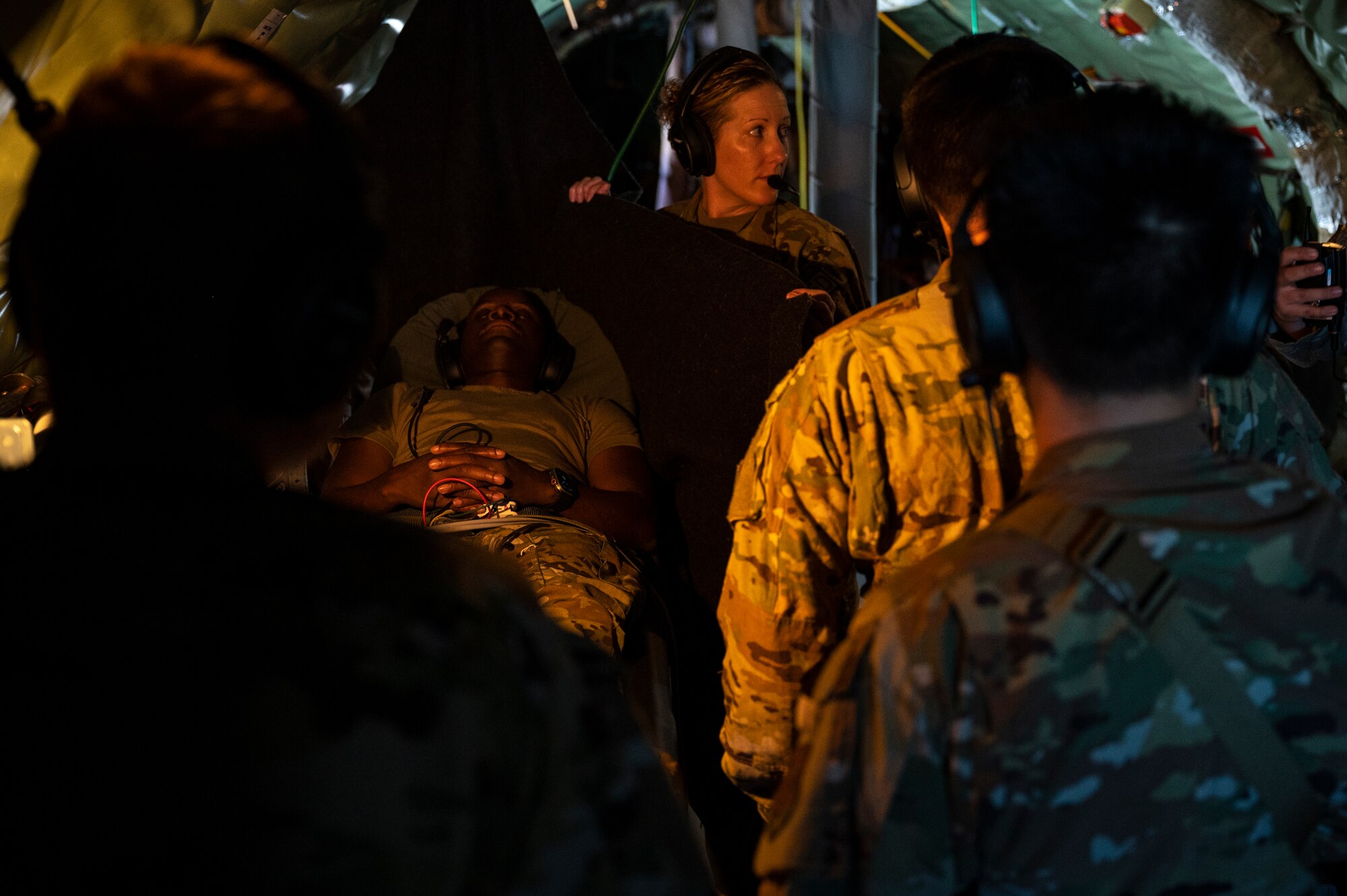 A group of Airmen gather around a patient