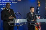 Two men in suits stand at lecterns.