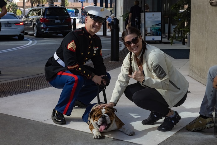 U.S. Marine Corps Pfc. Bruno, the mascot for Marine Corps Recruit Depot San Diego, and his handler, Sgt. Jesse Carter-Powell, a combat graphic specialist at MCRD, pose for a photo during a Veterans Day Parade near Downtown, San Diego, Nov. 12, 2023. The mascot’s job is to boost morale, participate in outreach work, and attend events and ceremonies. (U.S. Marine Corps photo by Lance Cpl. Jacob B. Hutchinson)
