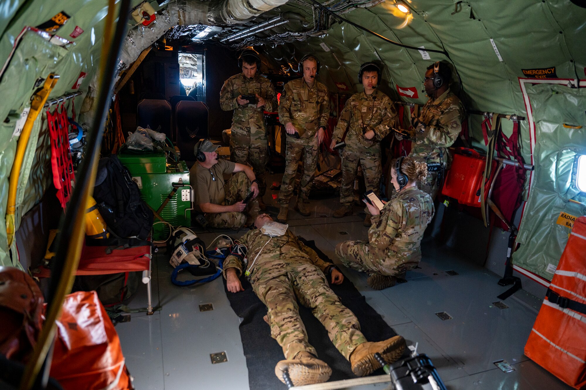 Airmen gather around a patient