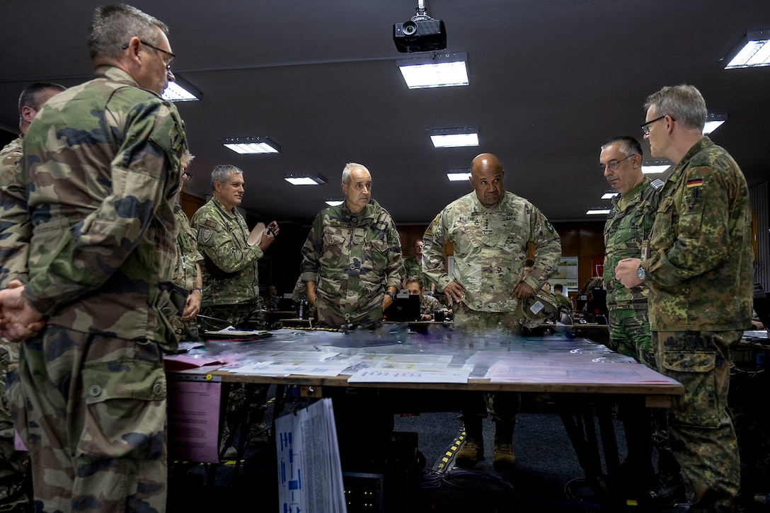 Senior officers talk while standing around a table.