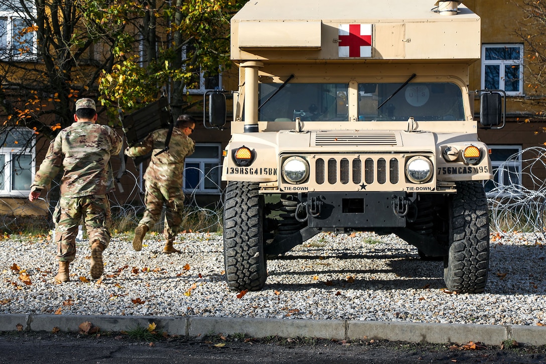 Soldiers rush medical supplies to a waiting humvee ambulance during a mass casualty training event.