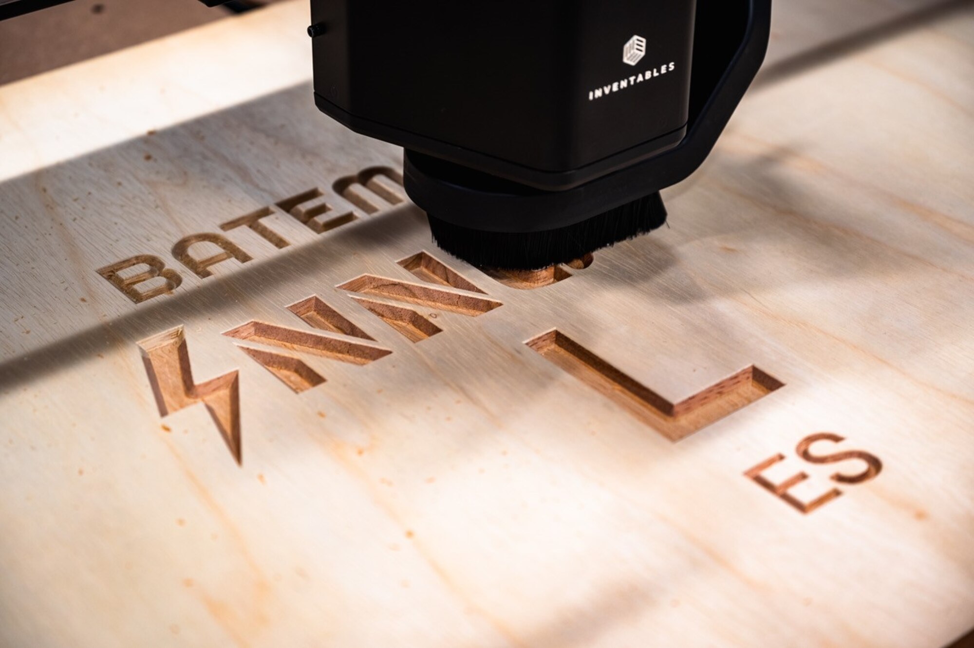 A laser engraver burns a letter into wood.