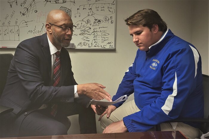 Photo of Fowler and another person sitting down talking over a document