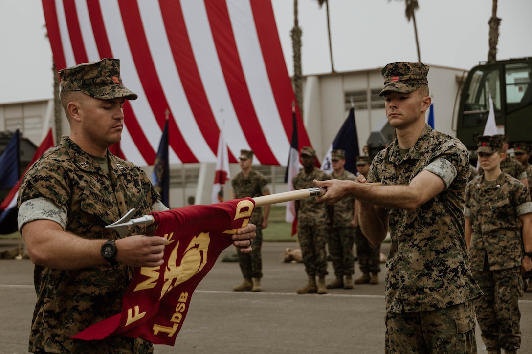 U.S. Marine Corps Capt. Chase Montambo, a logistics officer with 1st Distribution Support Battalion, Combat Logistics Regiment 1, 1st Marine Logistics Group, unfurls a new company guide-on during a unit redesignation and activation ceremony at Camp Pendleton, California, Oct. 19, 2023. 1st Landing Support Battalion was redesignated to 1st DSB as part of the Commandant of the Marine Corps’ Force Design 2030 initiative. (U.S. Marine Corps photo by Cpl. Casandra Lamas)
