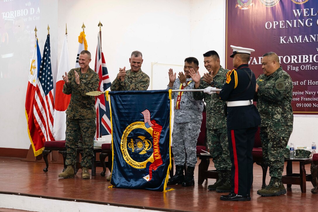 Leading representatives from the U.S. Marines Corps, Philippine Navy and Philippine Marine Corps celebrate unfurling the KAMANDAG 7 flag commencing the exercise during the opening ceremony on Fort Bonifacio, Manila, Philippines, Nov. 9, 2023. KAMANDAG is an annual Philippine Marine Corps and U.S. Marine Corps-led exercise aimed at improving bilateral readiness and mutual capabilities in the advancement of a Free and Open Indo-Pacific. This year marks the seventh iteration of this exercise and includes participants from Japan, the Republic of Korea, and observers from the United Kingdom. (U.S. Marine Corps photo by Sgt. Shaina Jupiter)