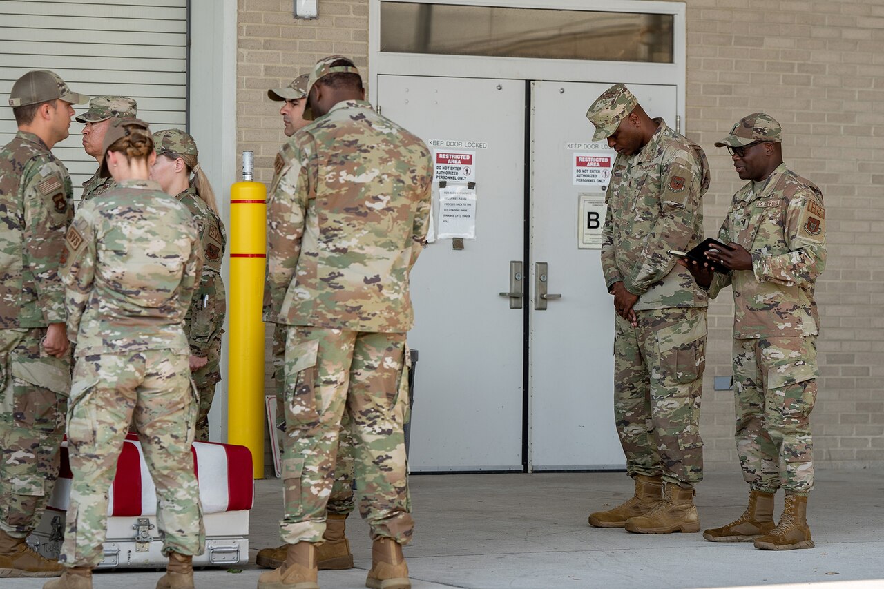 Several people cross their hands and bow their heads in prayer.