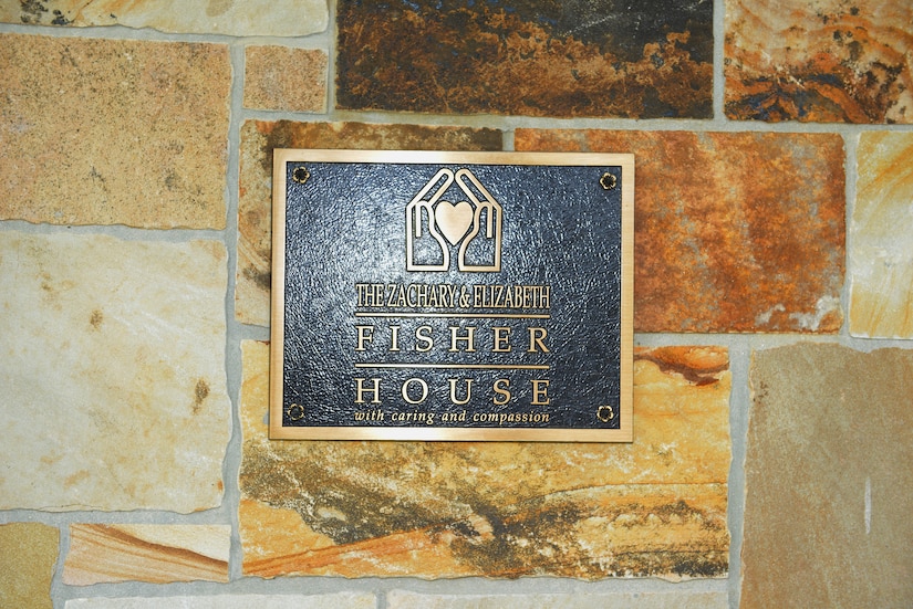 A plaque attached to a brick wall reads, “The Zachary and Elizabeth Fisher House.”