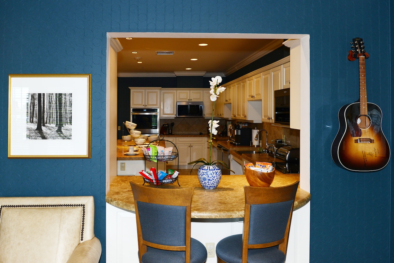 A breakfast bar makes way to a large kitchen. A guitar hangs on a wall.