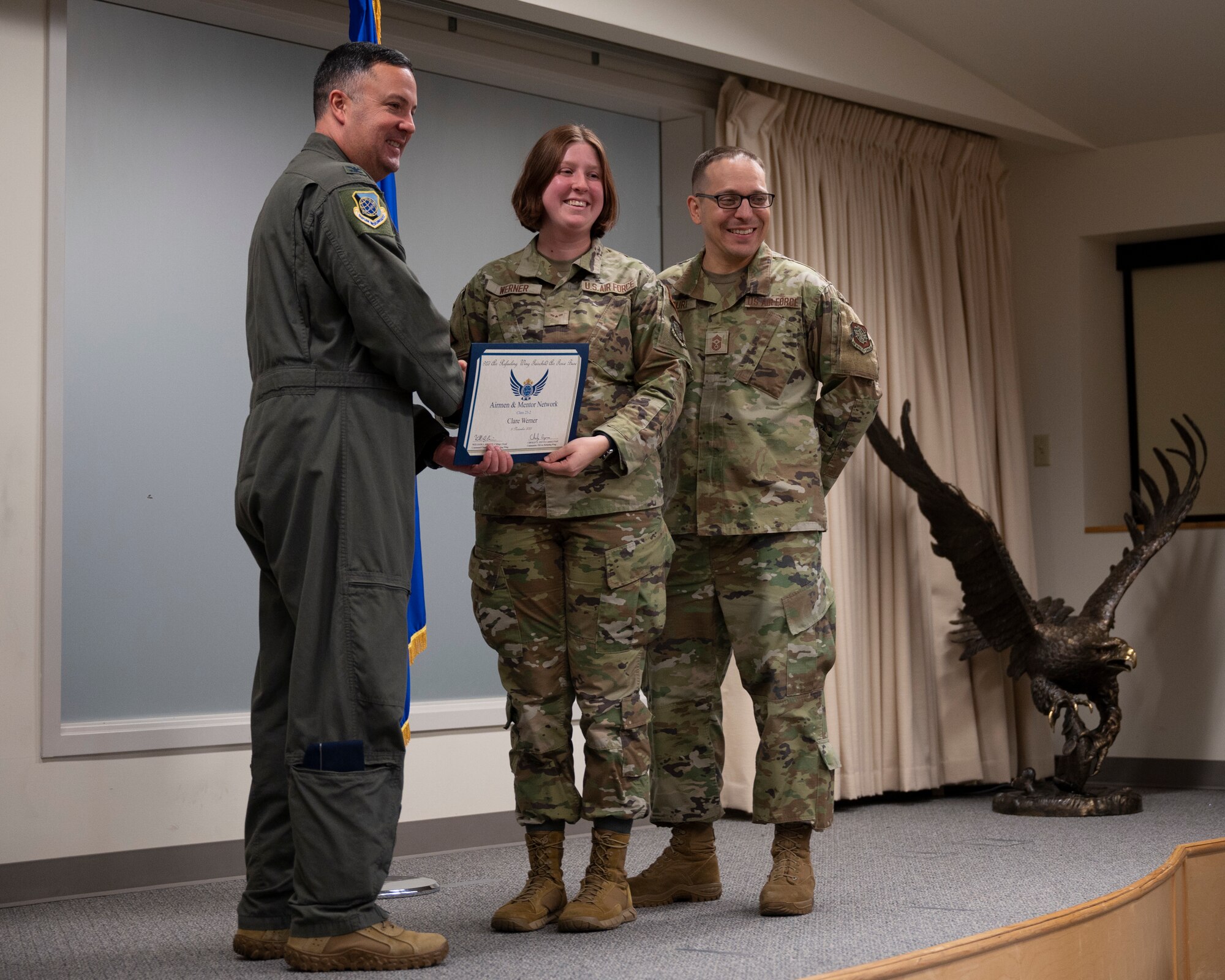 An Airman, deputy commander and command chief pose together with a certificate.