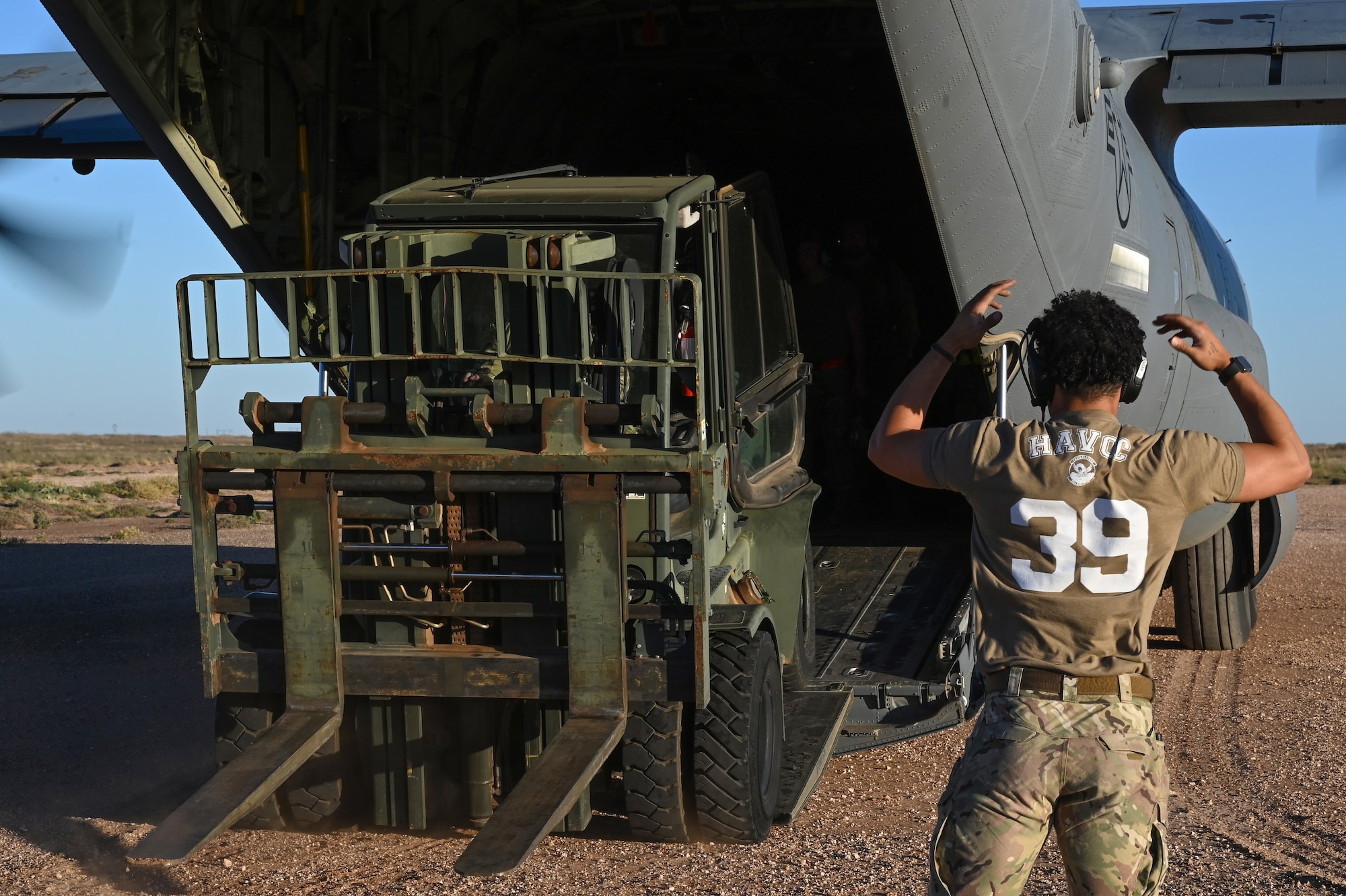 Senior Airman Darius Anthony, 39th Airlift Squadron loadmaster, guides a forklift off of a C-130J Super Hercules at Melrose Range, New Mexico, Oct. 17, 2023, during exercise Dark Horizon. Members from the 317th Airlift Wing participated in exercise Dark Horizon, showcasing tactical airlift employment in a contested environment. (U.S. Air Force photo by Senior Airman Sophia Robello)