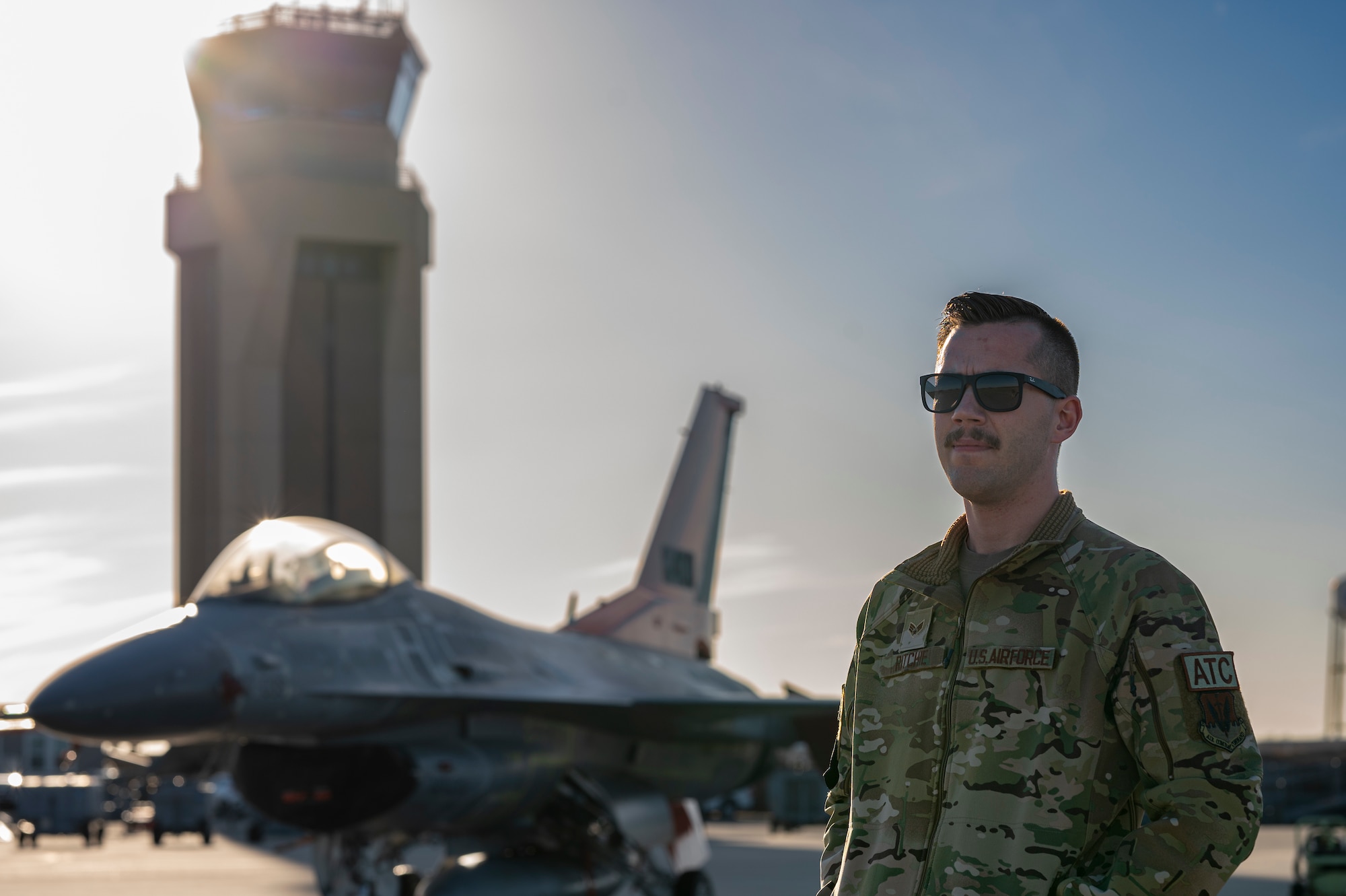 Airman poses in front of the air traffic control tower