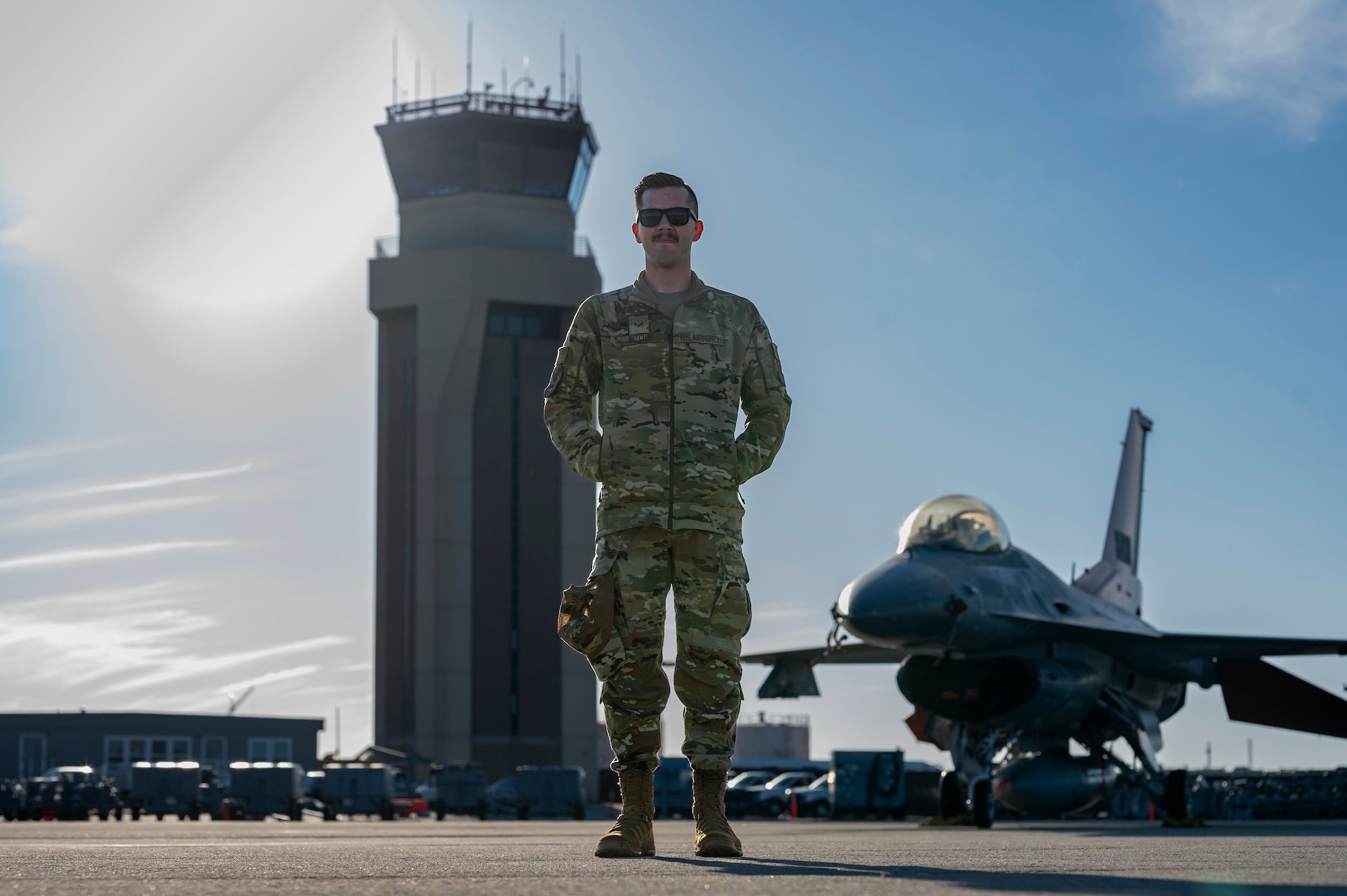 Airman poses in front of an air traffic control tower for a photo