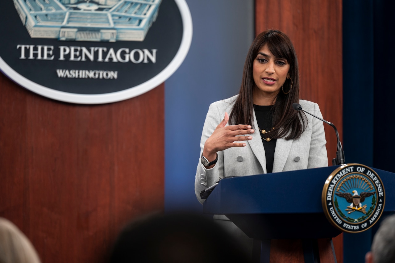 A woman speaks to an audience from a podium.