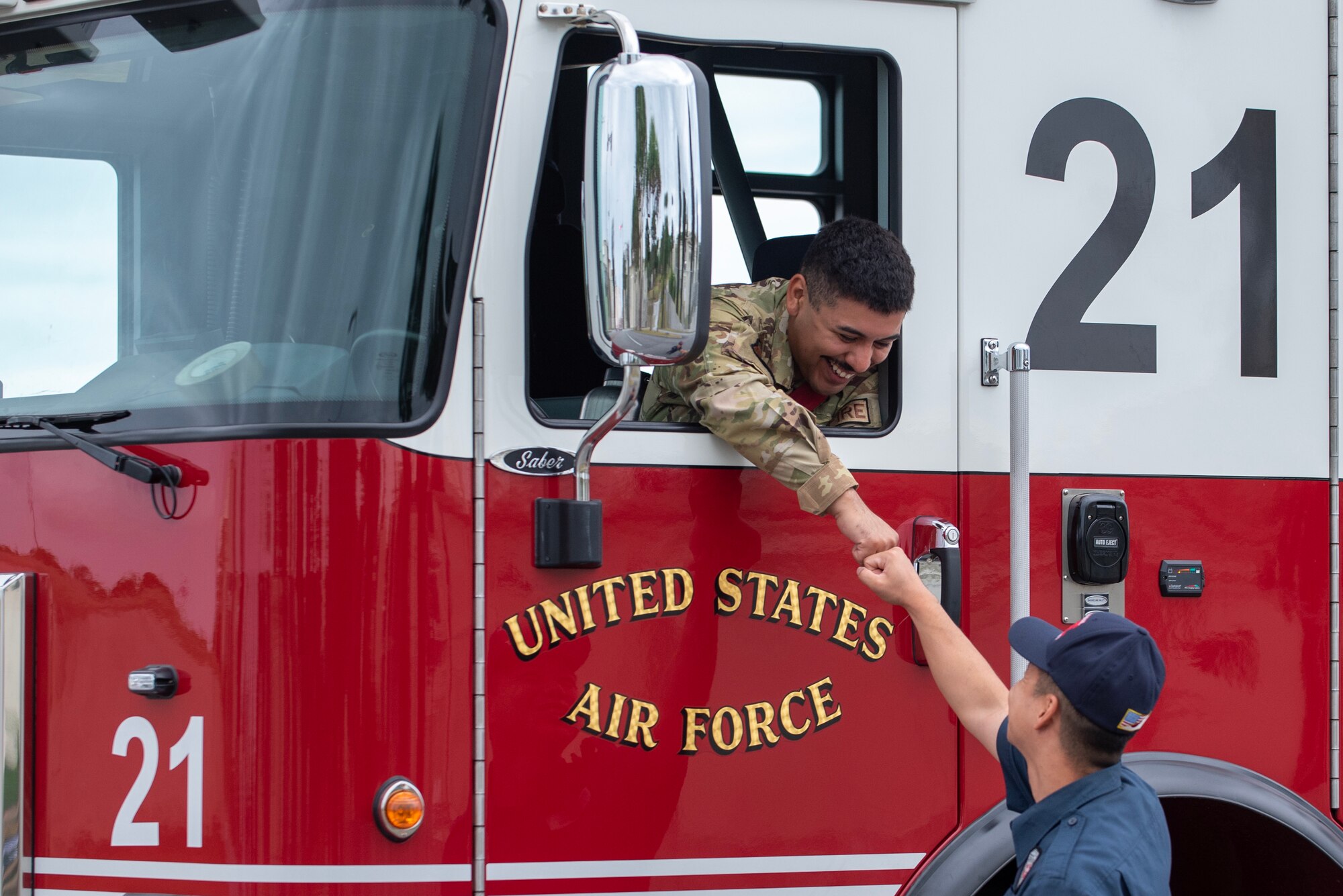 A fire fighter fist bumps spectators as his truck drives by during Kadena Air Base's Veterans Day Parade