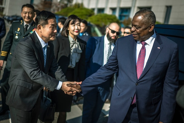 Two men in suits shake hands.