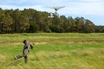 A service member throws a drone into the air.