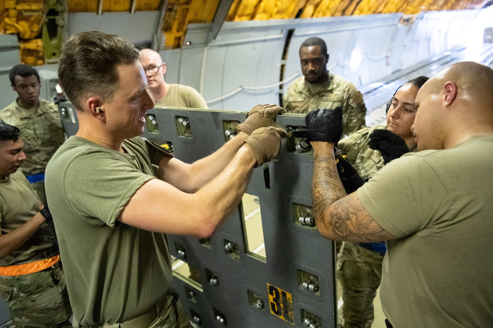 A group of Airmen unscrew omni-rollers from inside a KC-10 Extender