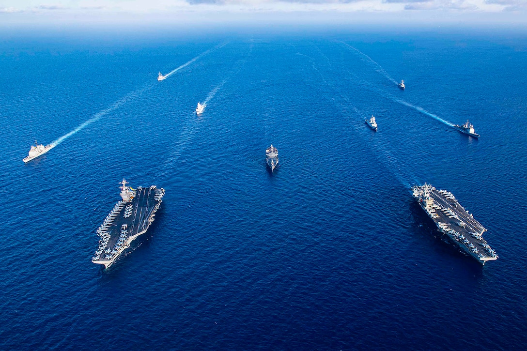 Ships sail in formation at sea.