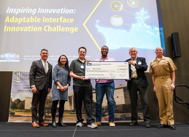 IMAGE: The ASRC Federal team won the $250,000 grand prize from Naval Surface Warfare Center Dahlgren Division’s (NSWCDD) Adaptable Interface Innovation Challenge. Pictured from left to right, NSWCDD Technical Director Dale Sisson Jr., SES, Executive Director, Program Executive Office for Integrated Warfare Systems Van Hendrey, SES, ASRC’s John Frankel, Orest Ukrainsky and Yu Verissimo and Chief of Naval Research Rear Adm. Kurt Rothenhaus.