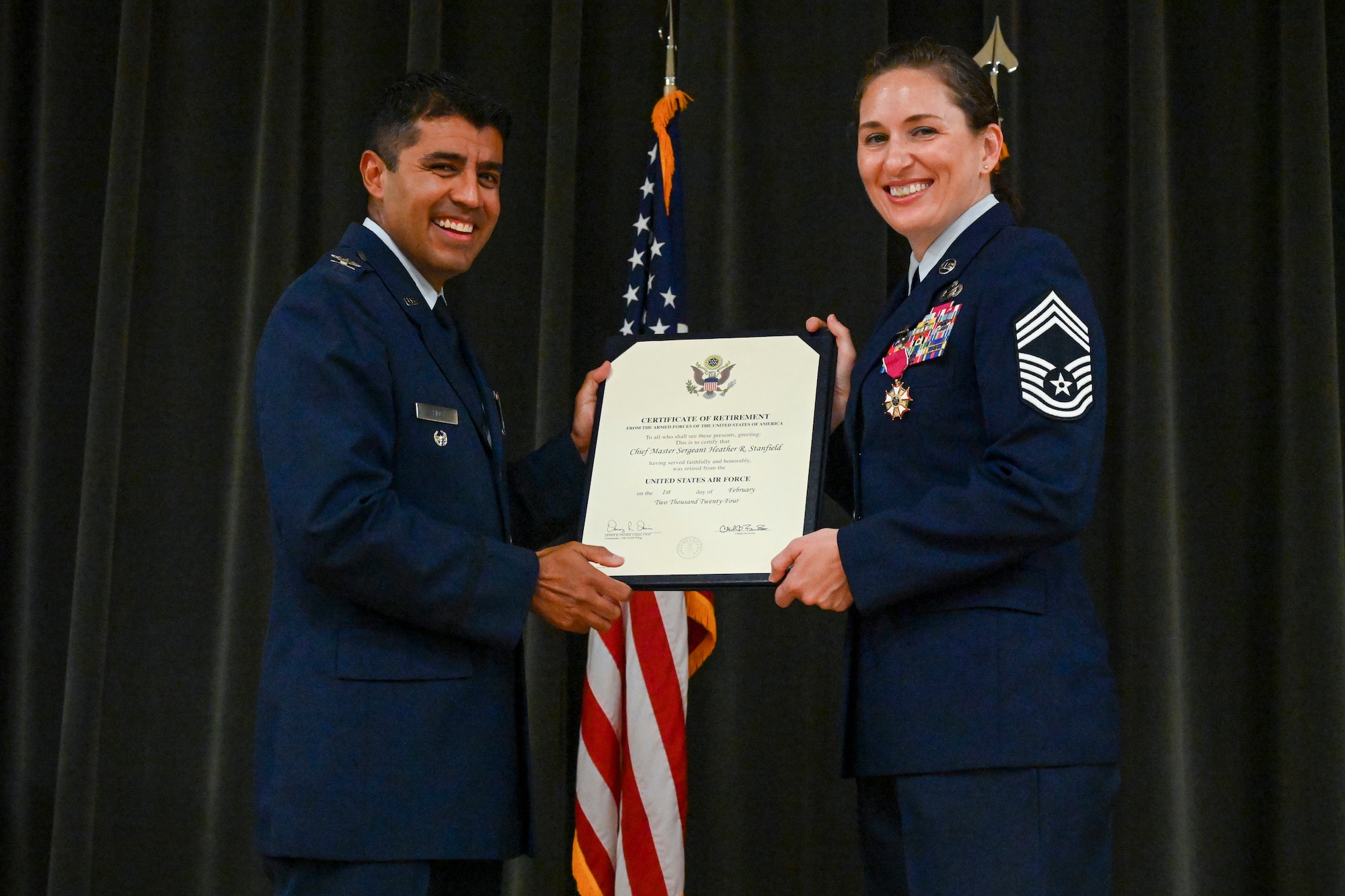 Col. Sergio Rios, 78th Air Base Wing deputy commander, left, presents Chief Master Sgt. Heather Stanfield, 19th Mission Support Group senior enlisted leader, right, with her certificate of retirement