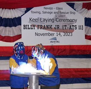 Billy Frank Jr. (T-ATS 11) Ship Sponsor Peggen Frank (at left) looks on as Austal welder Brandon Auld traces her initials onto a ceremonial keel plate.