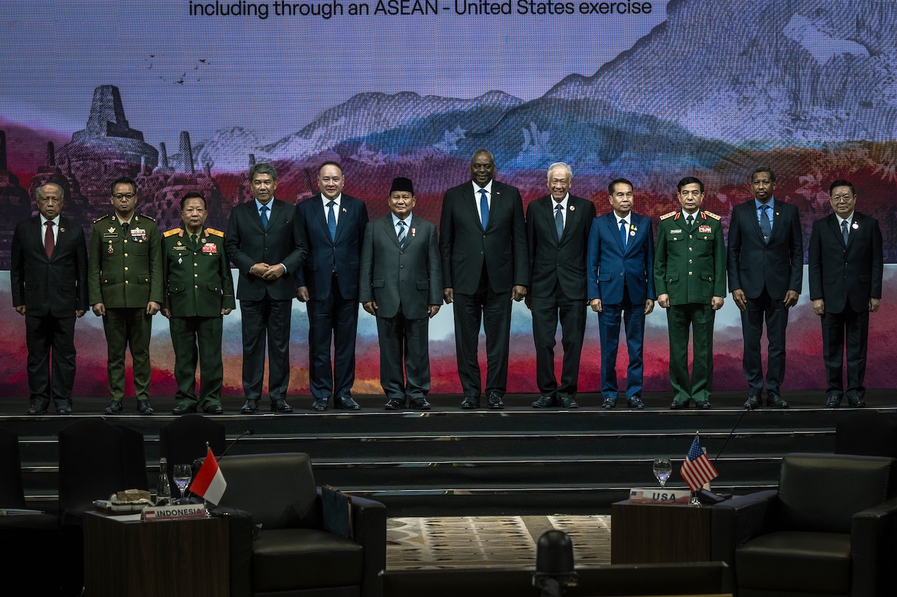 Men in suits and foreign military uniforms pose together for a photograph.