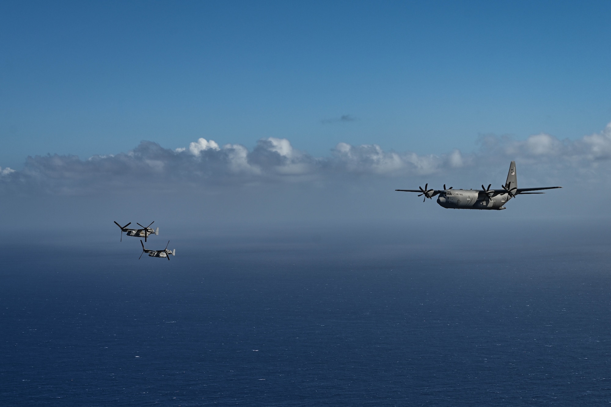 A group of military aircraft fly beside each other over the ocean