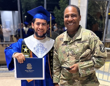 Army Future Soldier holding diploma standing next to Army recruiter on graduation day