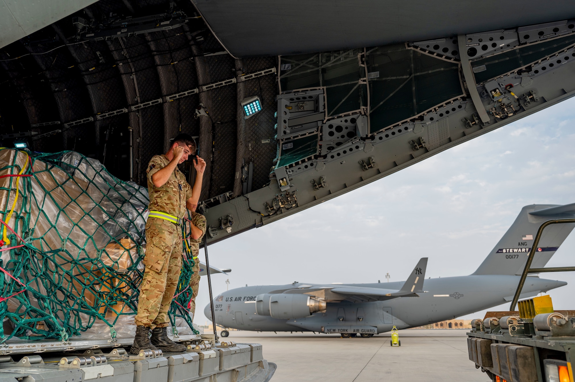A Royal Air Force logistic mover guides a U.S. Air Force K-Loader in the back of a RAF A400M Atlas.