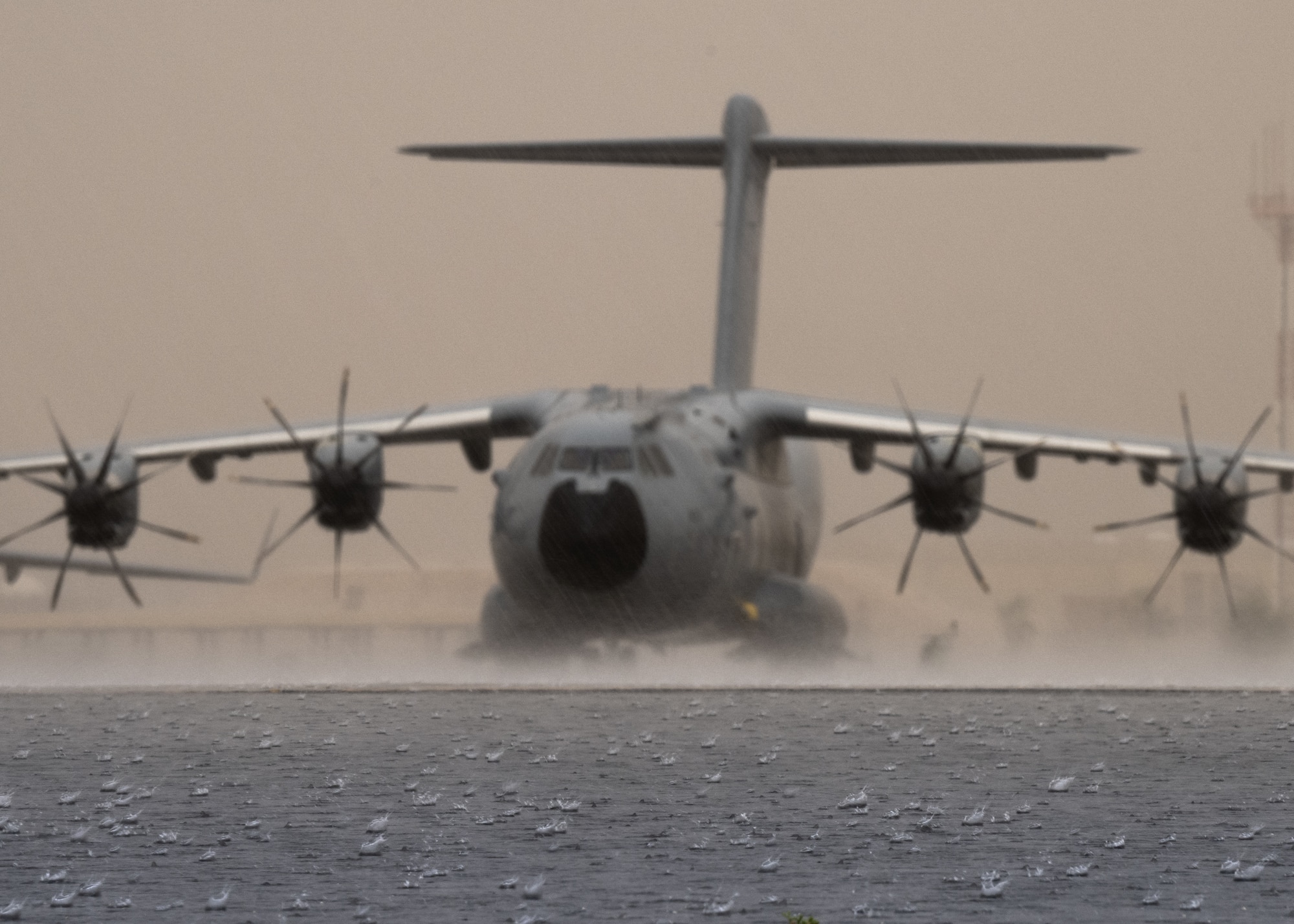A Royal Air Force A400 Atlas is shown parked on the flight line during a rain shower.