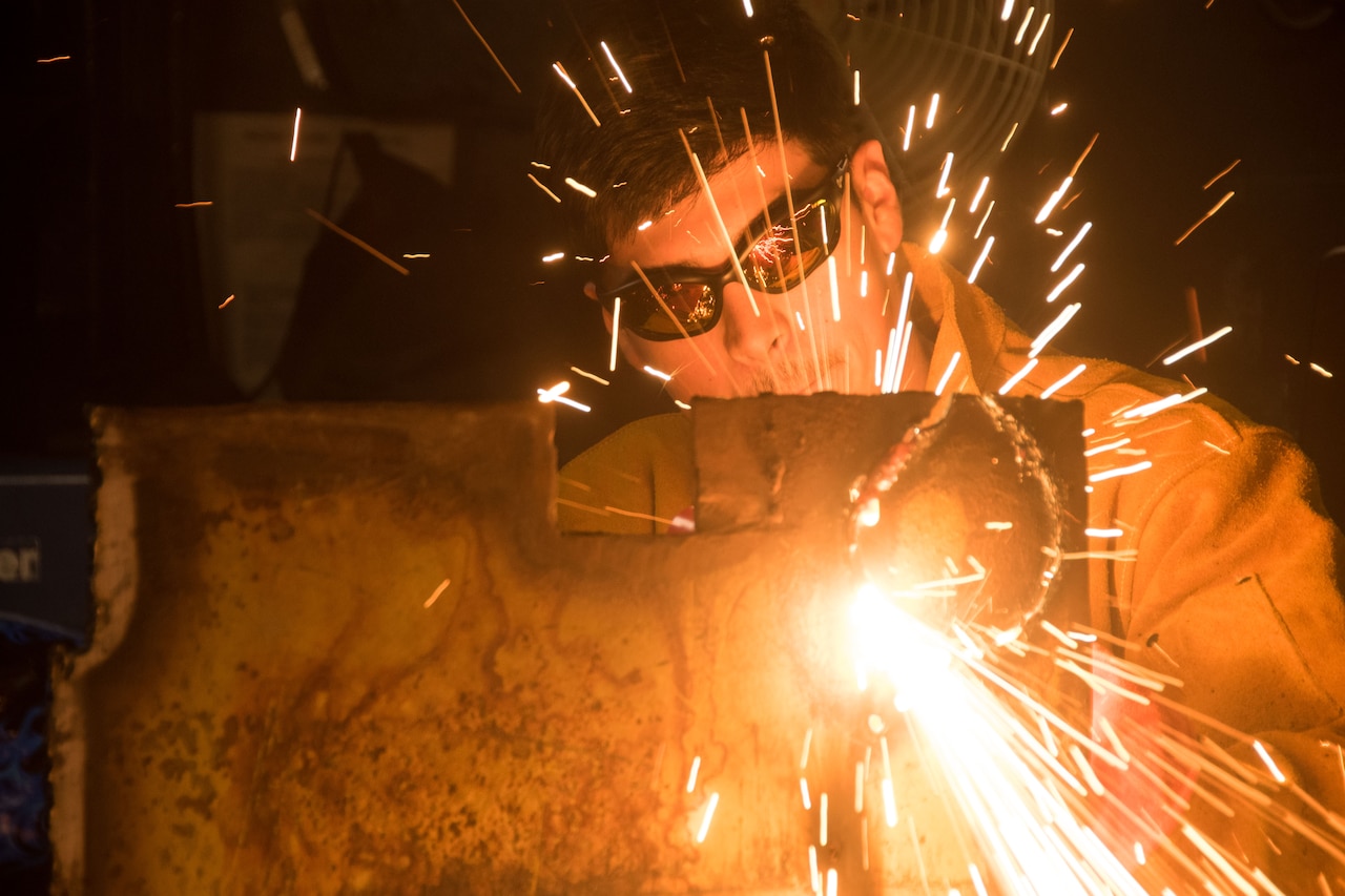 Sparks fly as sailor welds metal.