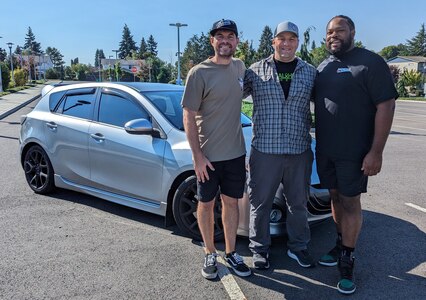 Evan Beckerman (left), Hull Technician 1st Class Justin Reinhardt (center), and Gary King Jr. (Right) stand in front of Reinhardt’s car prior to the remodel.