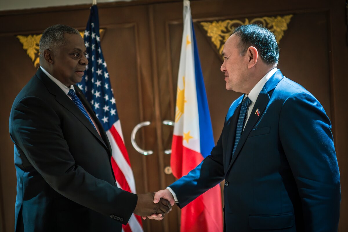 Two men in suits shake hands.