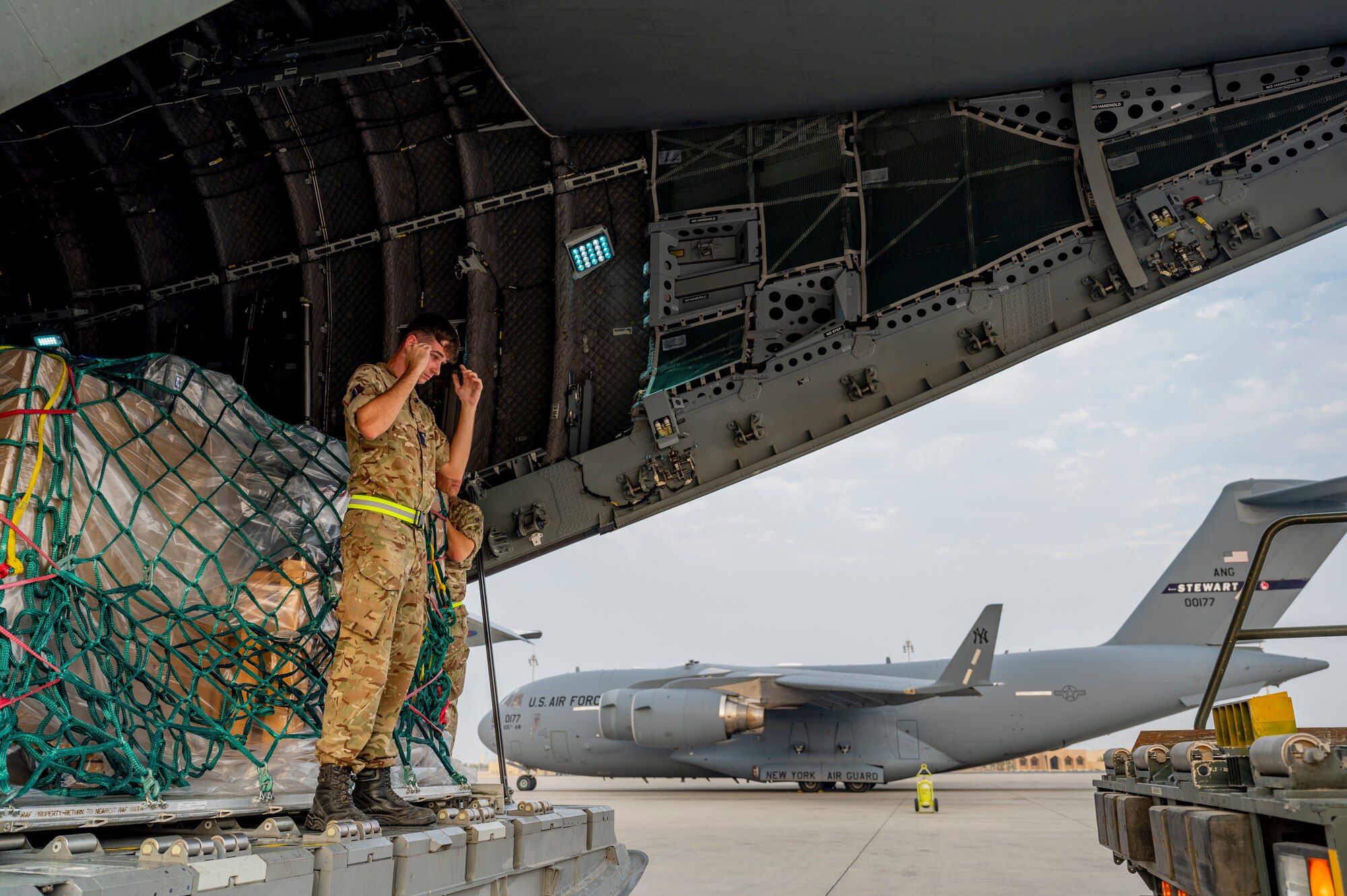 A Royal Air Force logistic mover guides a U.S. Air Force K-Loader in the back of a RAF A400M Atlas.