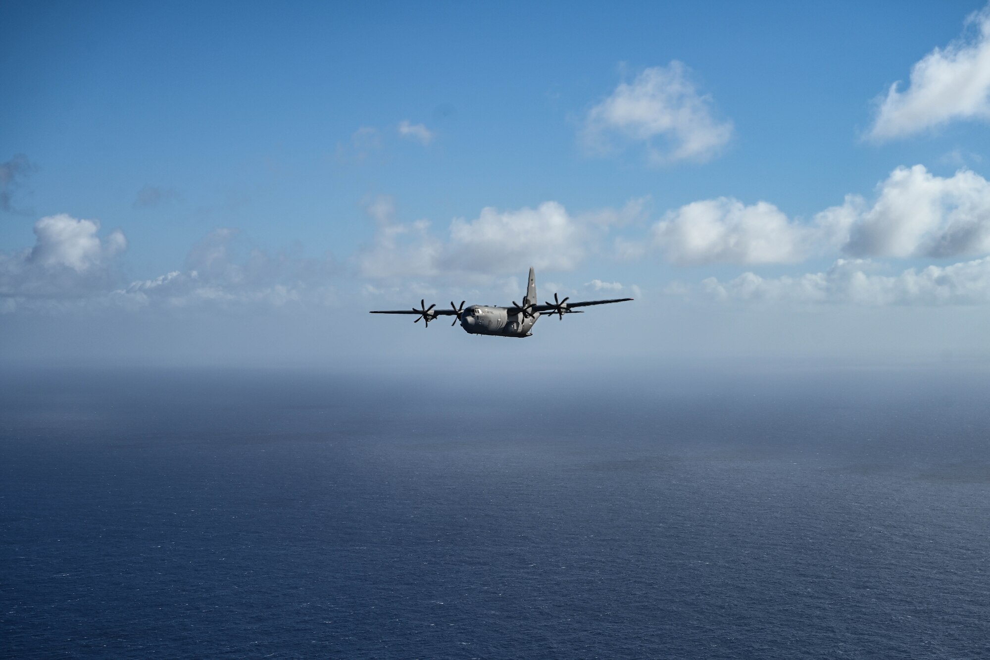 A military aircraft flies over an ocean