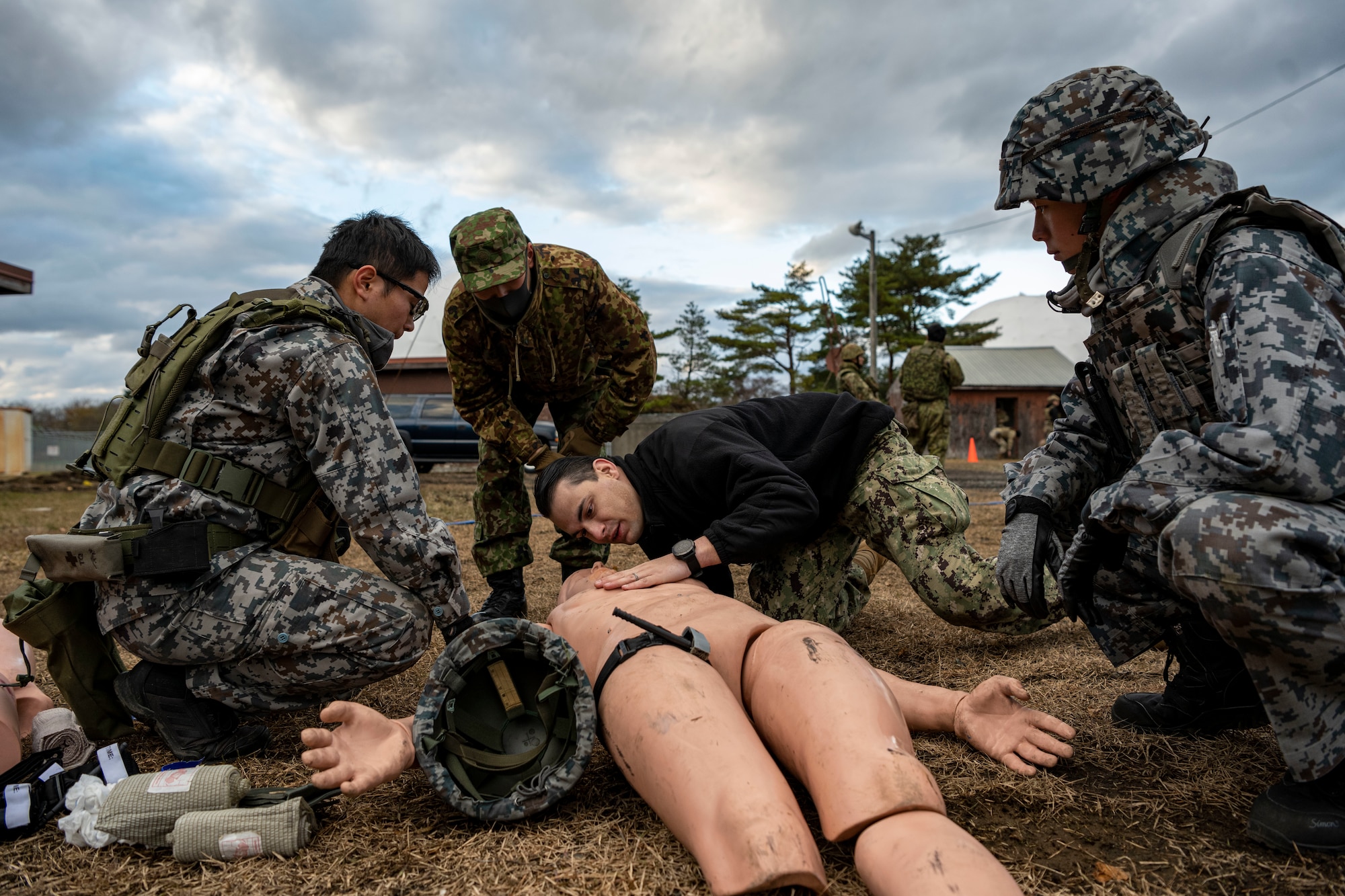 Service members conduct medical care to a training dummy.
