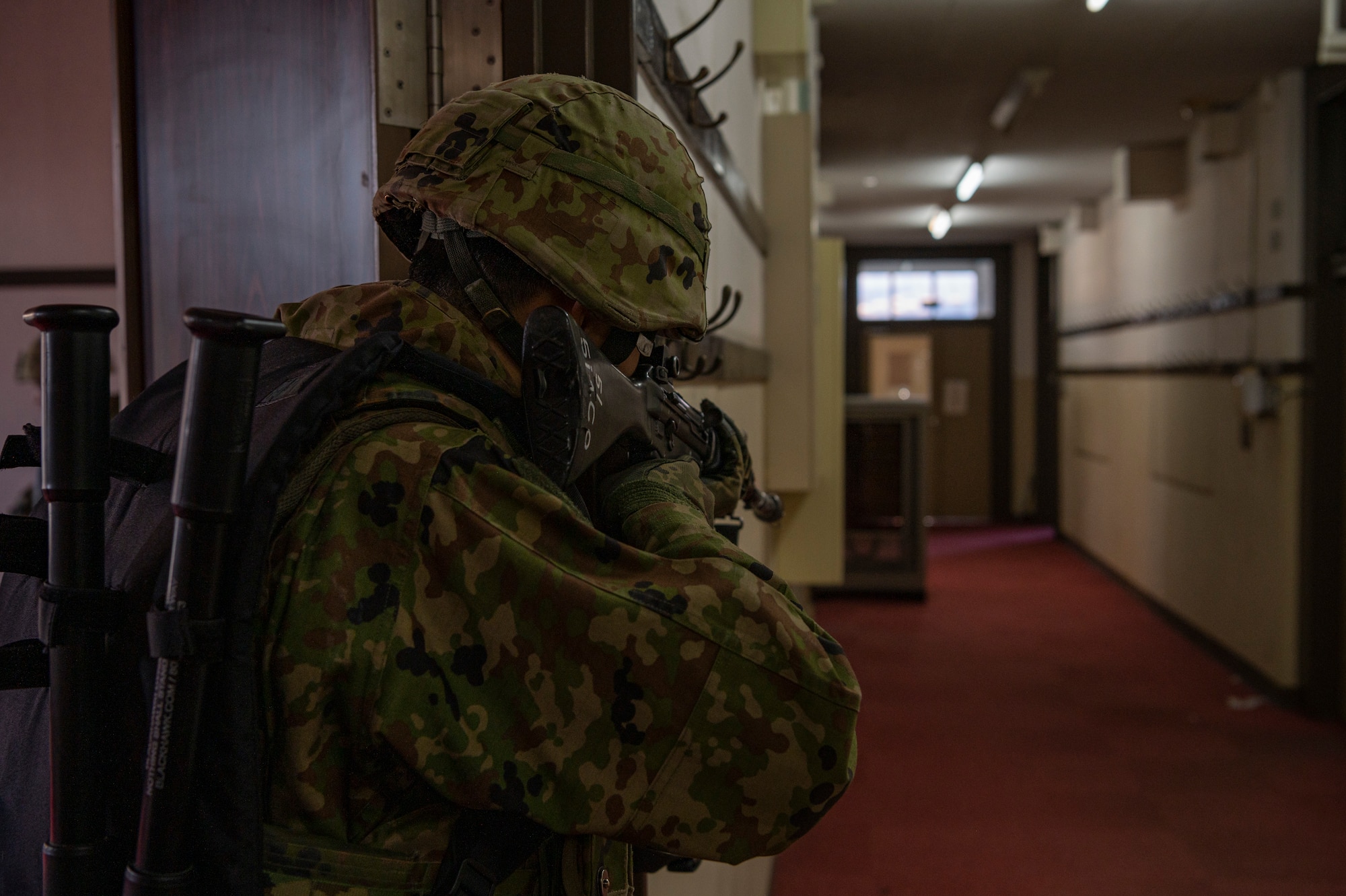 Military member covers a hallway during a training.