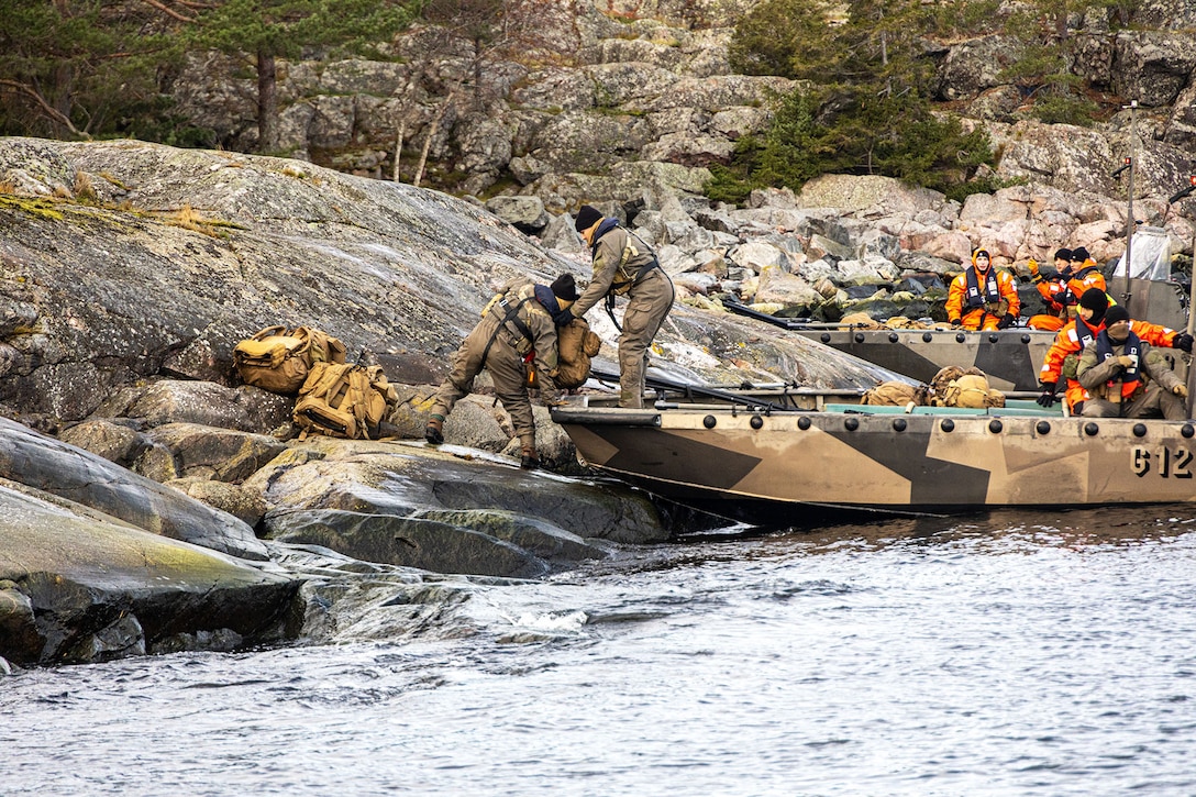 Marines unload gear from a landing craft during trial insertion and extraction drills.