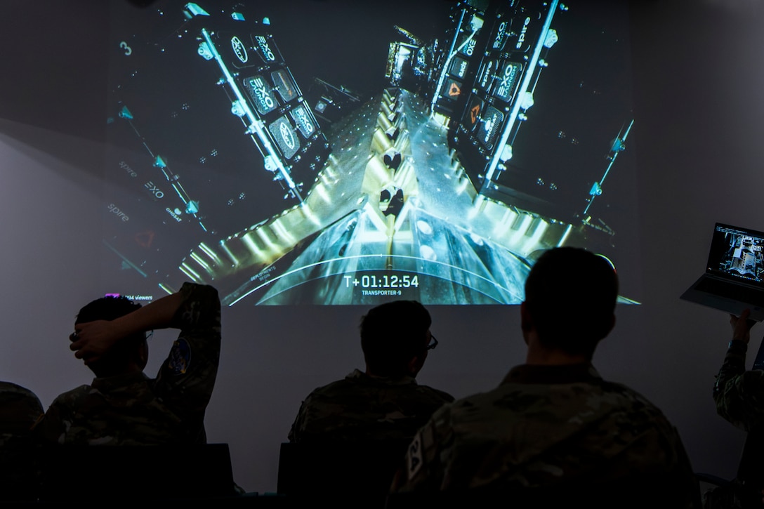 Cadets watch a satellite launch on a monitor.