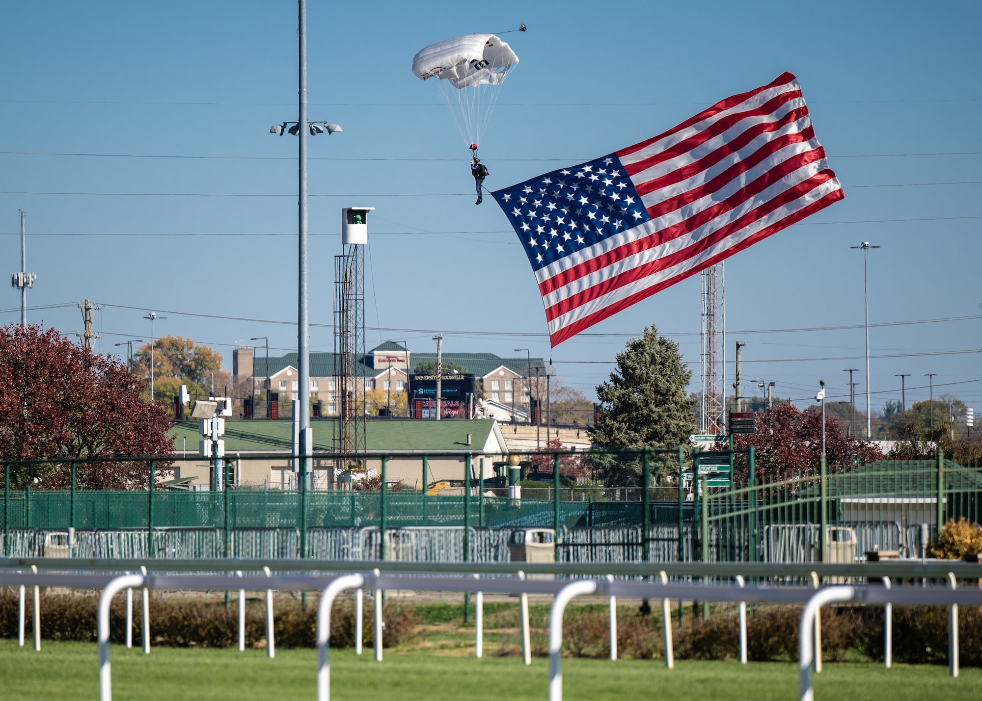 A parachutist skydives into Churchill Downs Racetrack in Louisville, Ky., Nov. 5, 2023, with a U.S. flag as part of Survivor’s Day at the Races, an annual event to honor family members who've lost loved ones in military service to the United States. Hosted with assistance from the Kentucky National Guard, the event drew more than 700 family members from 18 states. (U.S. Air National Guard photo by Dale Greer)
