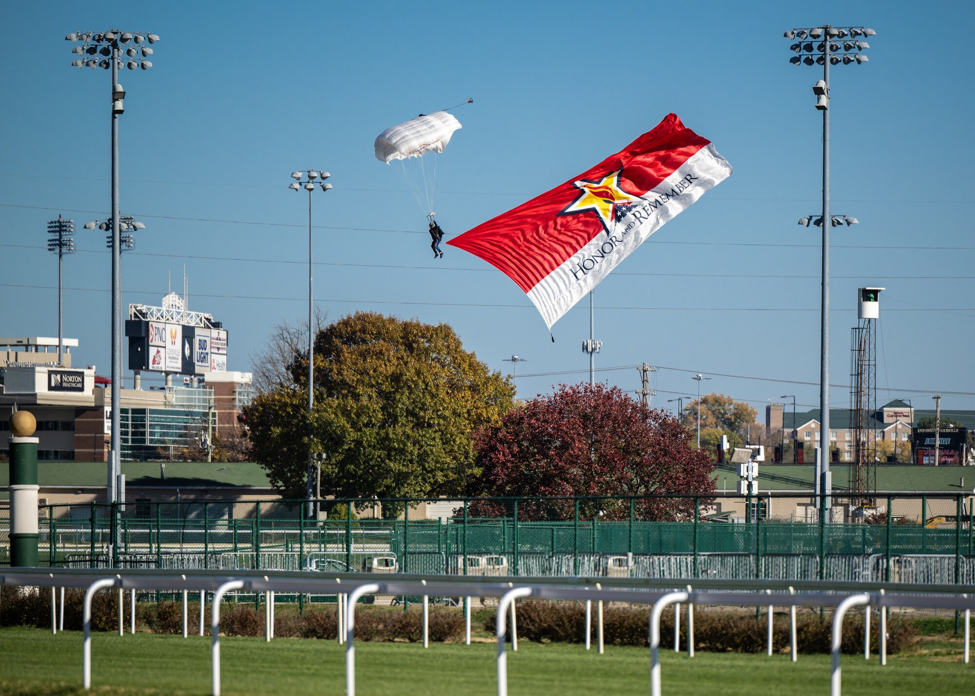 A parachutists skydives into Churchill Downs Racetrack in Louisville, Ky., Nov. 5, 2023, with the “Honor and Remember” banner  as part of Survivor’s Day at the Races, an annual event to honor family members who've lost loved ones in military service to the United States. Hosted with assistance from the Kentucky National Guard, the event drew more than 700 family members from 18 states. (U.S. Air National Guard photo bay Dale Greer)