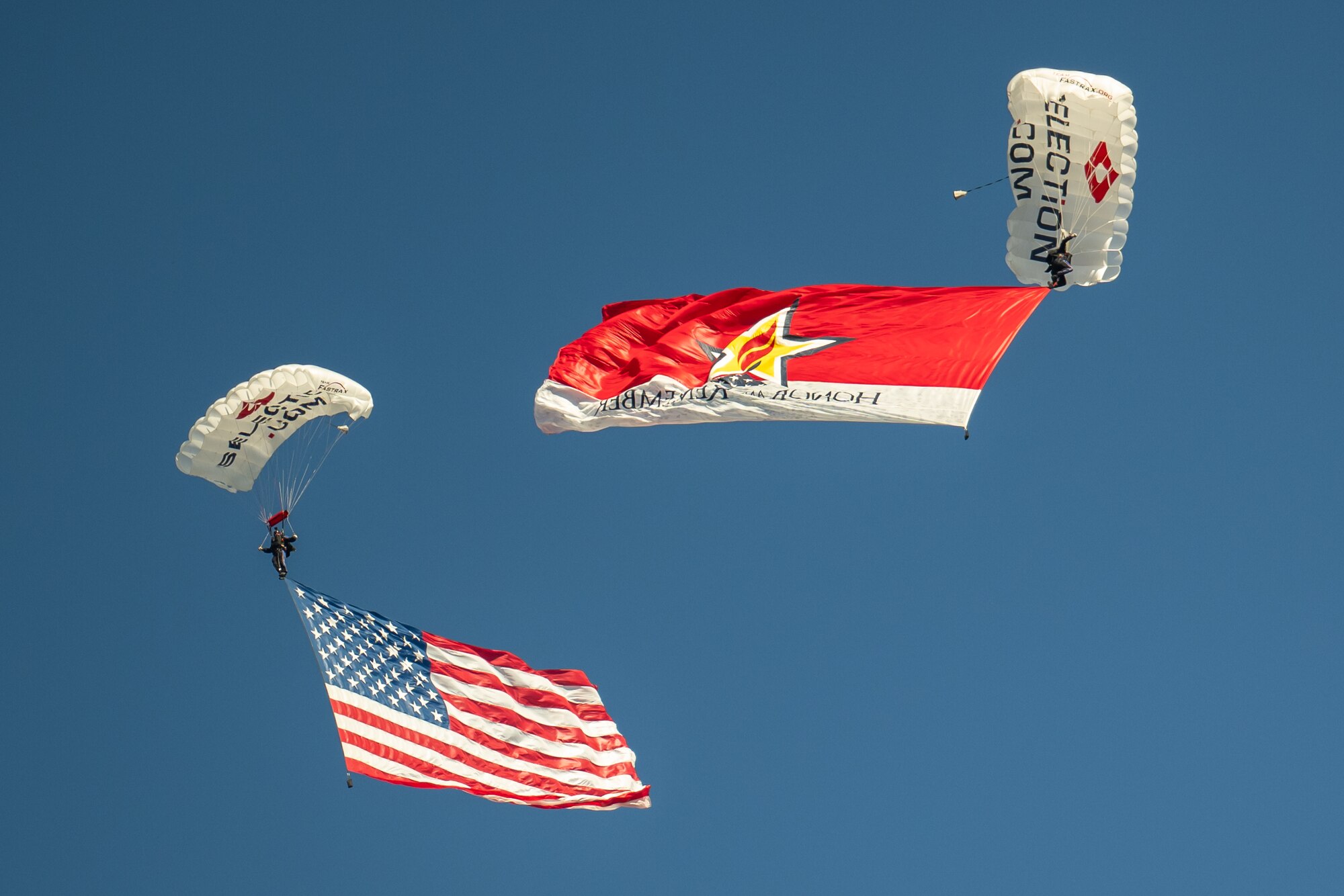 Parachutists skydive into Churchill Downs Racetrack in Louisville, Ky., Nov. 5, 2023, with a U.S. flag and the “Honor and Remember” banner as part of Survivor’s Day at the Races, an annual event to honor family members who've lost loved ones in military service to the United States. Hosted with assistance from the Kentucky National Guard, the event drew more than 700 family members from 18 states. (U.S. Air National Guard photo by Dale Greer)
